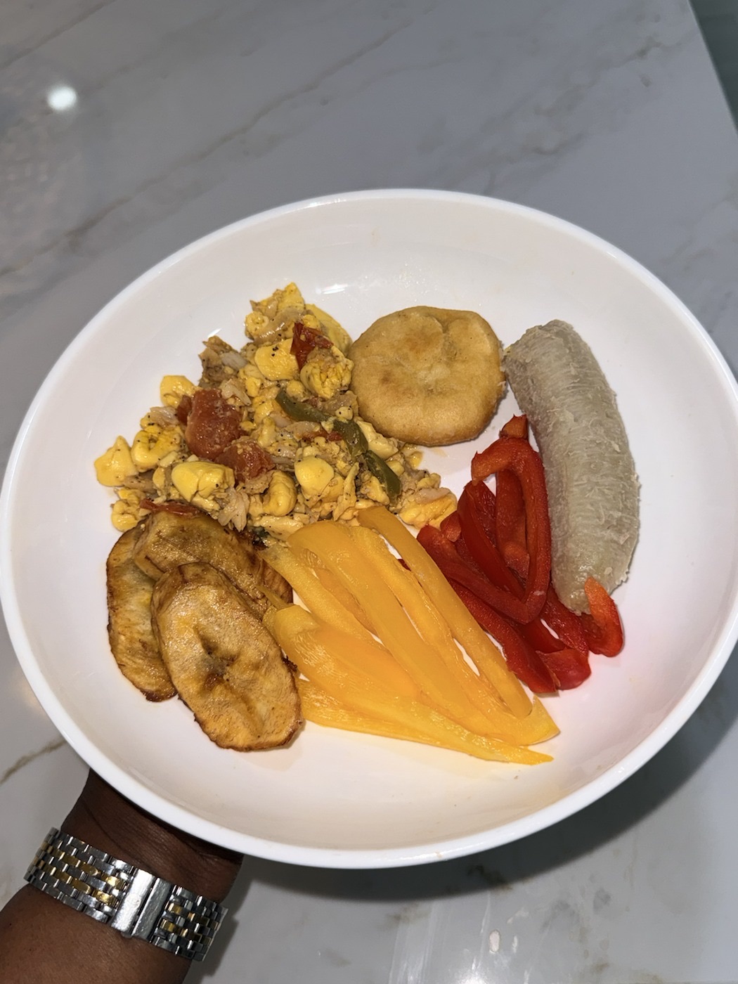A Caribbean breakfast with ackee and saltfish, plantain, boiled dumpling, and peppers